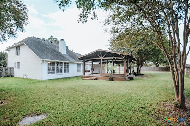 back of house with a gazebo, a deck, a fenced backyard, a chimney, and a yard