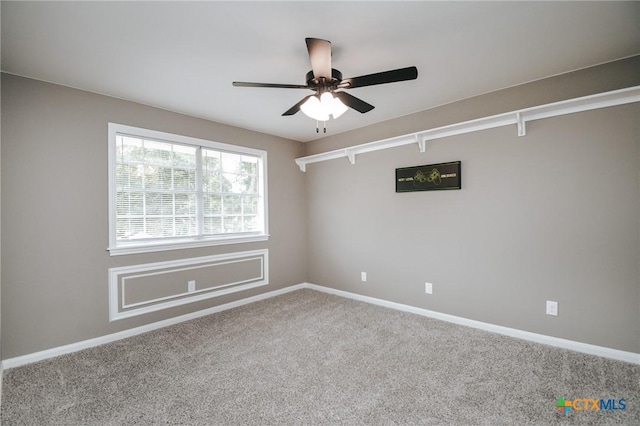 carpeted spare room with ceiling fan and baseboards