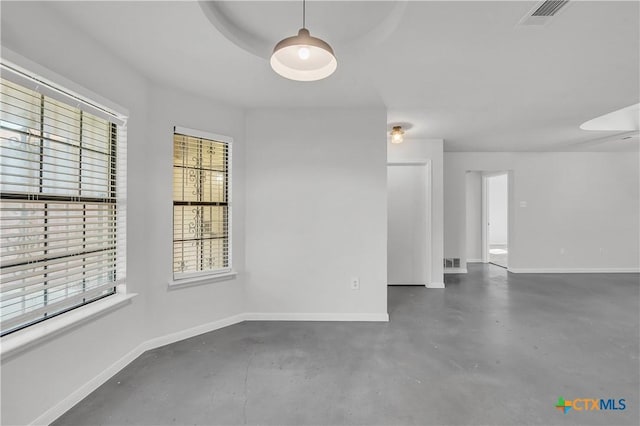 spare room featuring healthy amount of natural light, baseboards, and concrete floors