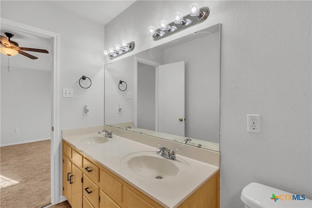 bathroom featuring toilet, double vanity, and ceiling fan
