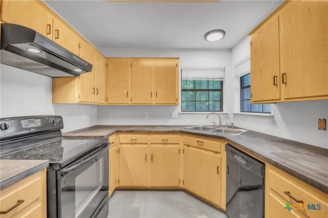 kitchen with black appliances, under cabinet range hood, a sink, and dark countertops