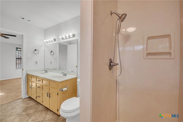 bathroom with tile patterned floors, toilet, a shower, double vanity, and a ceiling fan