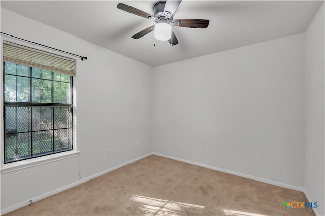spare room with light carpet, baseboards, and a ceiling fan