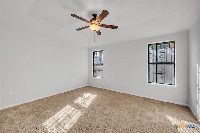 carpeted empty room featuring healthy amount of natural light, ceiling fan, and baseboards