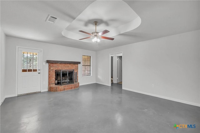 unfurnished living room featuring ceiling fan, baseboards, concrete flooring, a raised ceiling, and a fireplace