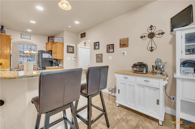 kitchen featuring light tile patterned floors, recessed lighting, white cabinetry, freestanding refrigerator, and light stone countertops