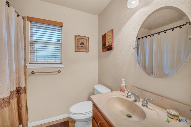 bathroom featuring toilet, vanity, and baseboards