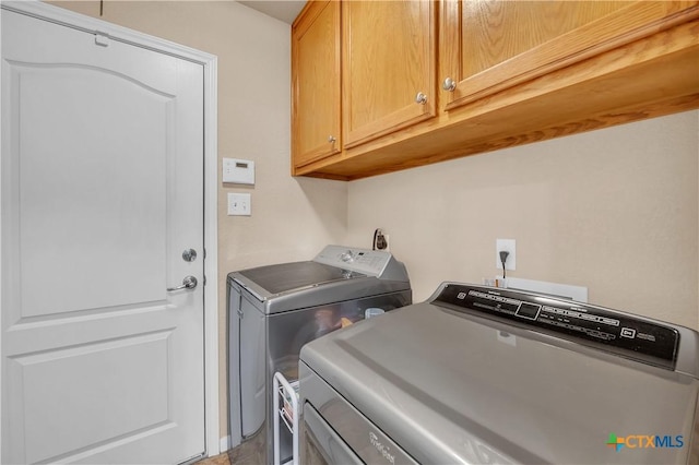 clothes washing area featuring independent washer and dryer and cabinet space