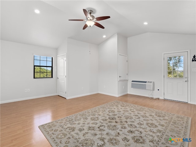 living room featuring vaulted ceiling, a wall unit AC, ceiling fan, and light hardwood / wood-style floors