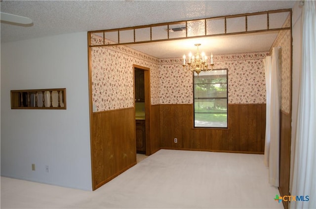 303 E 20th Ave, Belton, TX 76513 - carpeted spare room featuring wainscoting, wood walls, a chandelier, and a textured ceiling