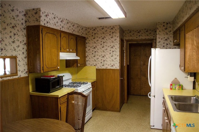 303 E 20th Ave, Belton, TX 76513 - kitchen with wallpapered walls, white range with gas cooktop, black microwave, under cabinet range hood, and wainscoting