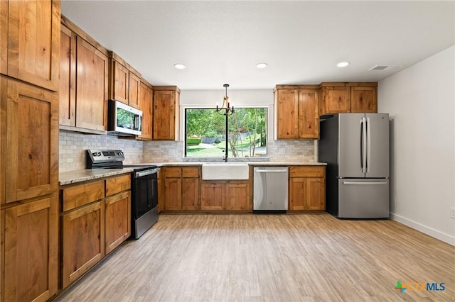 910 Cliffside Dr, Harker Heights, TX 76548 - kitchen with appliances with stainless steel finishes, light wood finished floors, a sink, brown cabinetry, and recessed lighting
