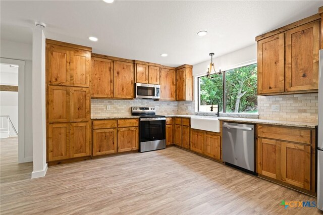 910 Cliffside Dr, Harker Heights, TX 76548 - kitchen featuring stainless steel appliances, brown cabinets, light wood-style floors, a sink, and decorative backsplash