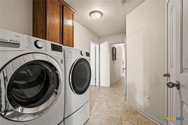 laundry room with separate washer and dryer, cabinets, and a textured ceiling