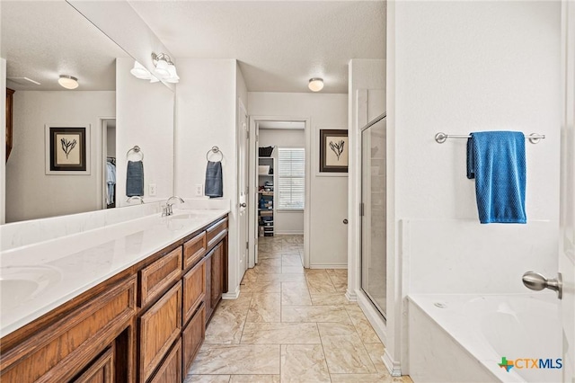 bathroom featuring vanity, independent shower and bath, and a textured ceiling