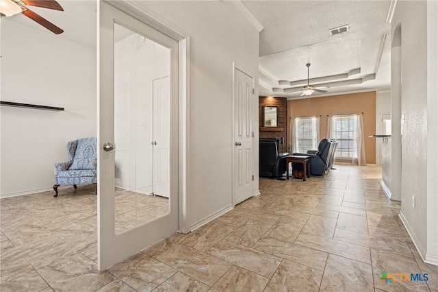 hallway with crown molding, a tray ceiling, and a textured ceiling