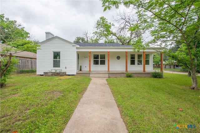 view of front of property featuring covered porch, a chimney, fence, and a front yard