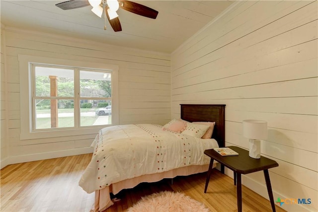 bedroom featuring baseboards, ceiling fan, light wood finished floors, and crown molding