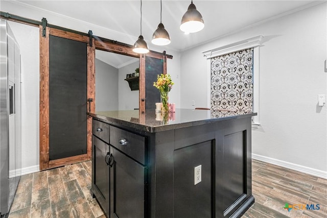 kitchen with a barn door, dark wood finished floors, dark cabinetry, and crown molding