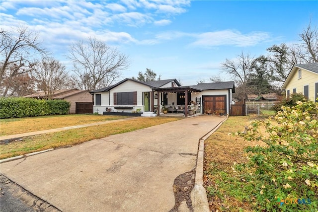 view of front of home with a front yard, concrete driveway, fence, and an attached garage