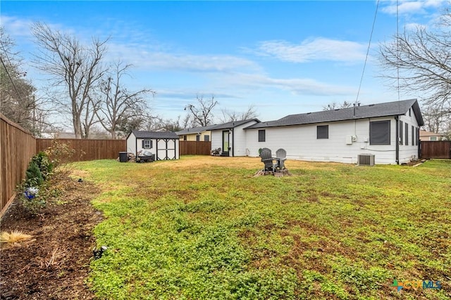 view of yard featuring central AC unit, a fenced backyard, a storage unit, and an outdoor structure