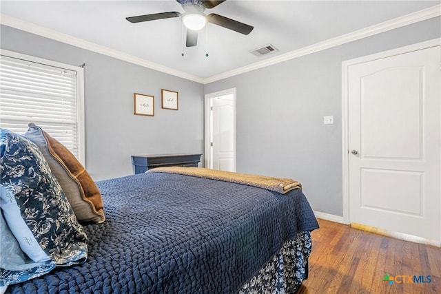 bedroom with crown molding, visible vents, ceiling fan, wood finished floors, and baseboards