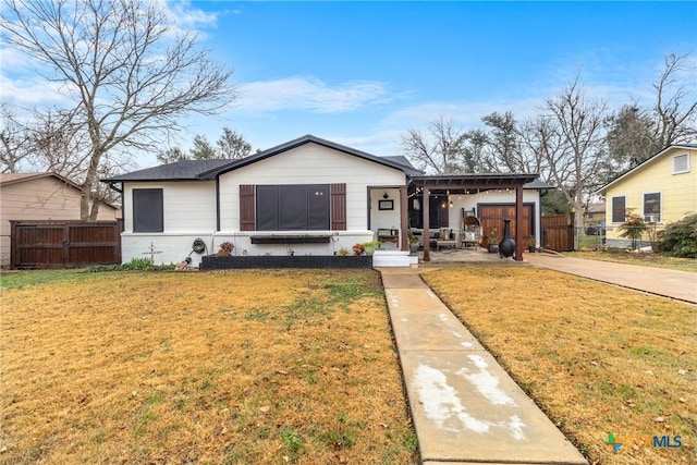 bungalow-style house featuring driveway, brick siding, fence, and a front yard