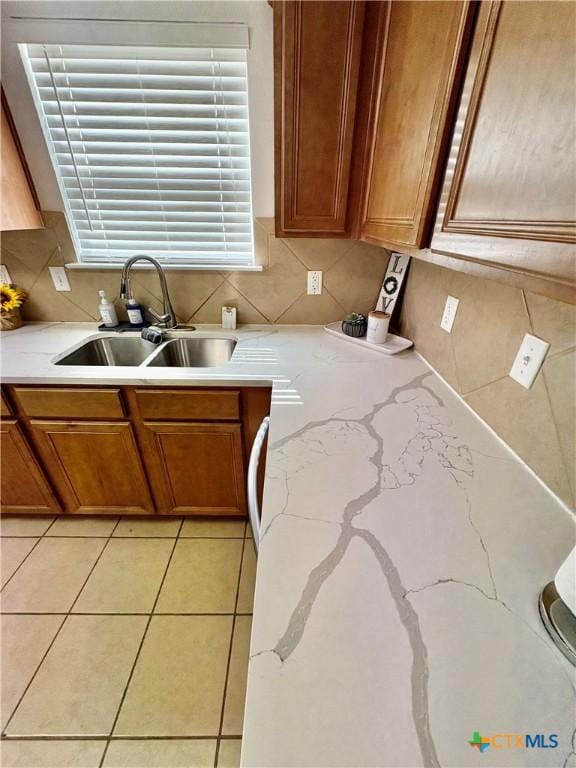 5902 Chuckwagon Cir, Killeen, TX 76542 - kitchen featuring a sink, brown cabinets, decorative backsplash, light stone countertops, and light tile patterned floors
