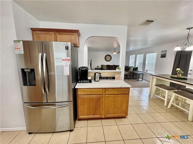 5902 Chuckwagon Cir, Killeen, TX 76542 - kitchen with stainless steel fridge, a ceiling fan, light tile patterned floors, brown cabinetry, and arched walkways