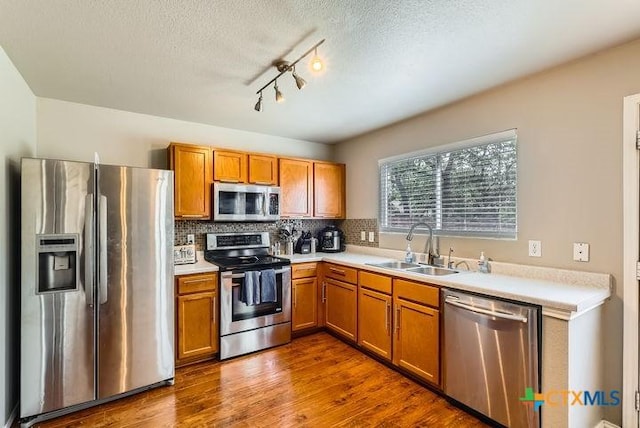 25923 Torch Lily, San Antonio, TX 78260 - kitchen featuring appliances with stainless steel finishes, a sink, brown cabinetry, light countertops, and a textured ceiling