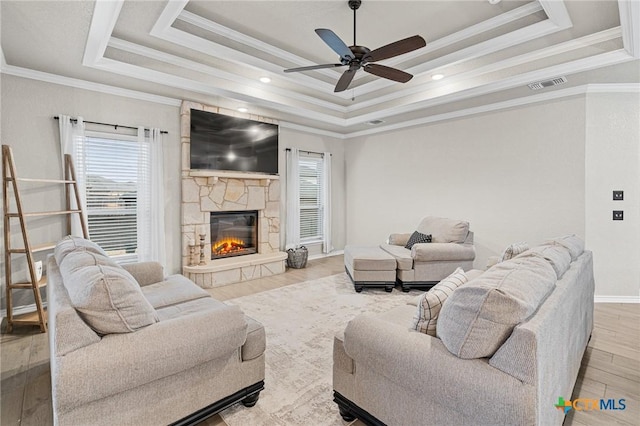 living room with light hardwood / wood-style floors, a raised ceiling, and ornamental molding