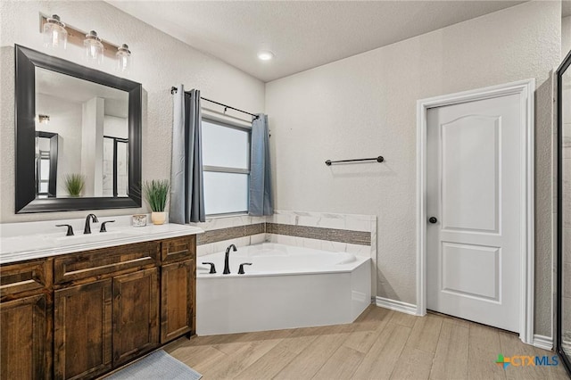 bathroom with vanity, hardwood / wood-style floors, a bathtub, and a textured ceiling