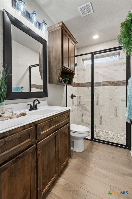 bathroom with vanity, wood-type flooring, a textured ceiling, and an enclosed shower