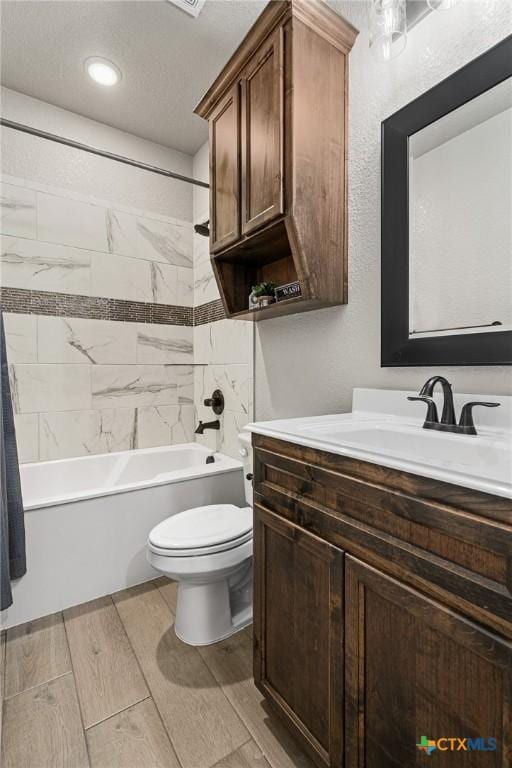 full bathroom featuring vanity, tiled shower / bath, and toilet