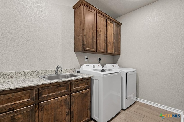 washroom featuring cabinets, washing machine and dryer, light hardwood / wood-style flooring, and sink