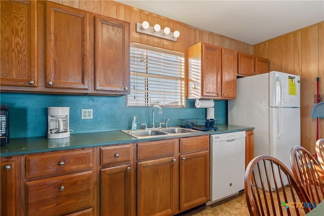 kitchen with sink, white appliances, and wood walls