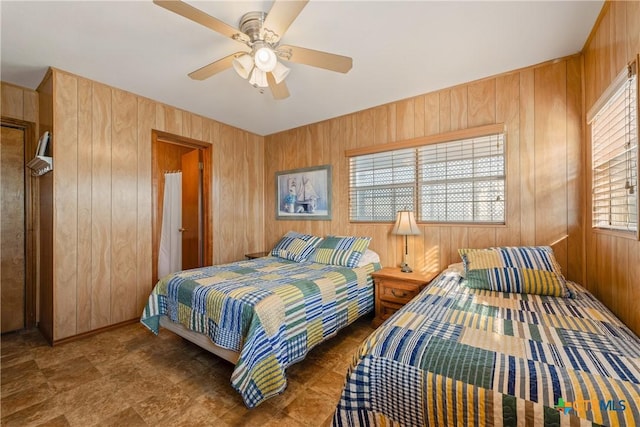 bedroom featuring ceiling fan and wood walls