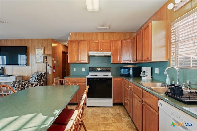 kitchen with backsplash, white appliances, sink, and wood walls