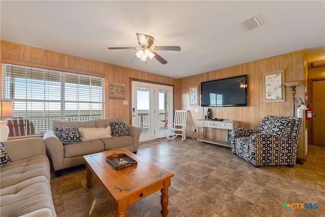 living room with ceiling fan and wooden walls