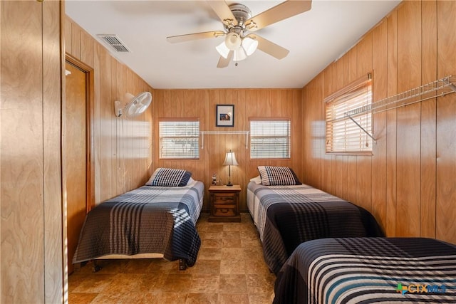 bedroom with ceiling fan and wood walls