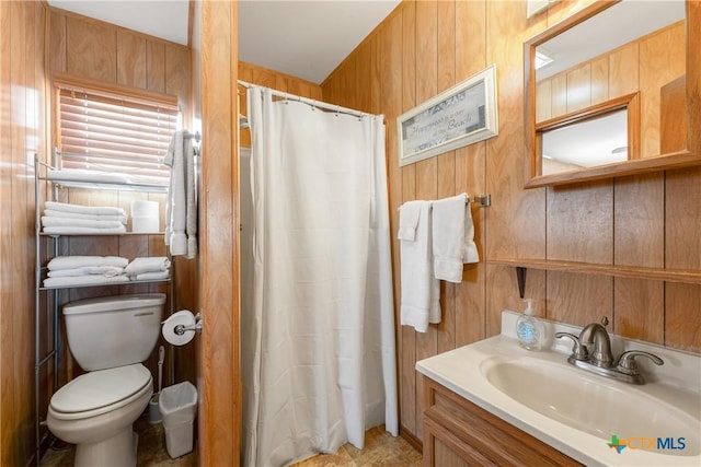 bathroom with vanity, toilet, a shower with shower curtain, and wood walls