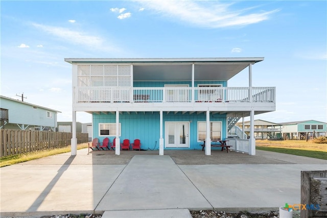 rear view of property featuring a patio, a balcony, and french doors