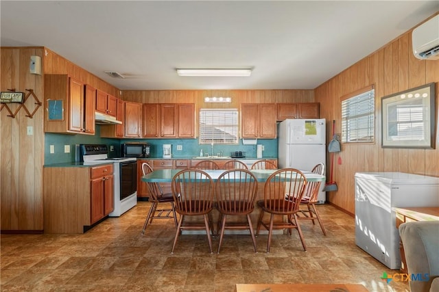 kitchen featuring sink, a wall mounted air conditioner, white appliances, and wood walls