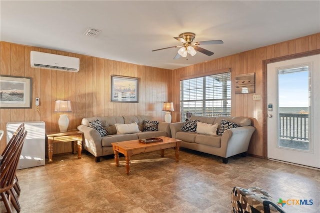 living room featuring ceiling fan, a wall unit AC, and wood walls