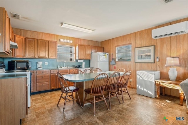 kitchen with sink, electric range, a wall unit AC, a kitchen breakfast bar, and white fridge