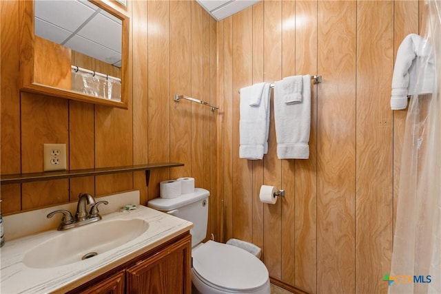 bathroom featuring vanity, toilet, and wood walls