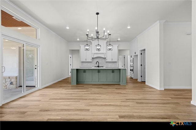 15938 Salado Dr, Temple, TX 76502 - kitchen featuring green cabinets, a chandelier, backsplash, light wood-style flooring, and a center island with sink