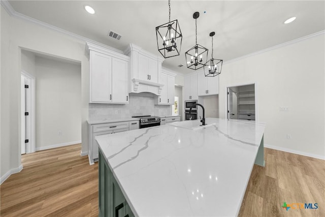 15938 Salado Dr, Temple, TX 76502 - kitchen featuring light wood finished floors, appliances with stainless steel finishes, a chandelier, white cabinetry, and tasteful backsplash
