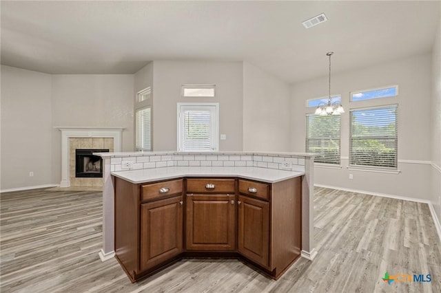7617 Amber Meadow Loop, Temple, TX 76502 - kitchen with light countertops, light wood-type flooring, a tile fireplace, and a chandelier