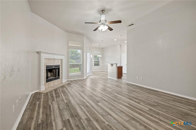 7617 Amber Meadow Loop, Temple, TX 76502 - unfurnished living room with wood finished floors, baseboards, ceiling fan, a tiled fireplace, and a textured wall